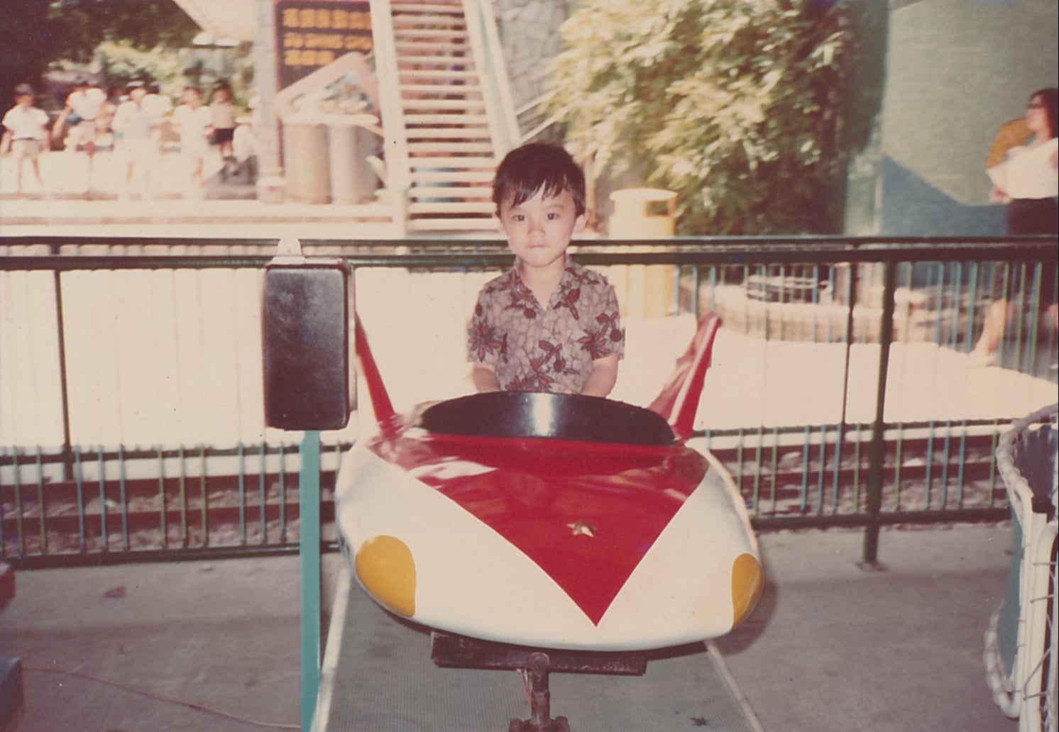 A boy playing a car ride at a funfair 1980s Hong Kong