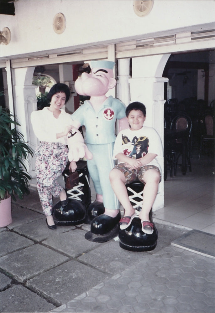 A girl and a boy posing with Popeye statue 1990s – cinematic memory preservation